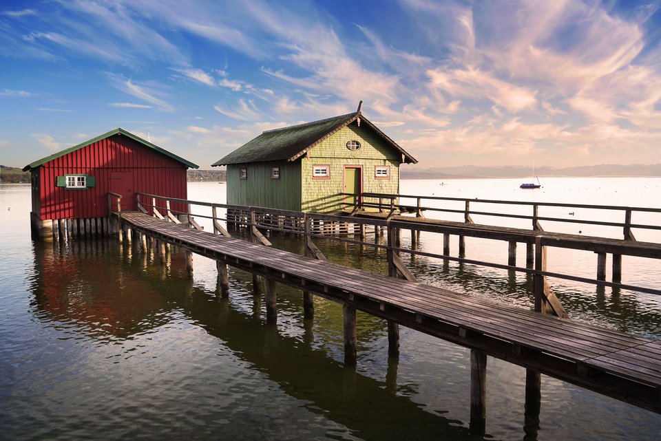 Steg, Bootshaus und Alpen am Ammersee.